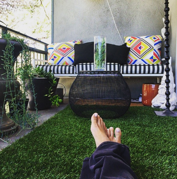 Bare feet on green artificial turf balcony — soft and comfortable surface